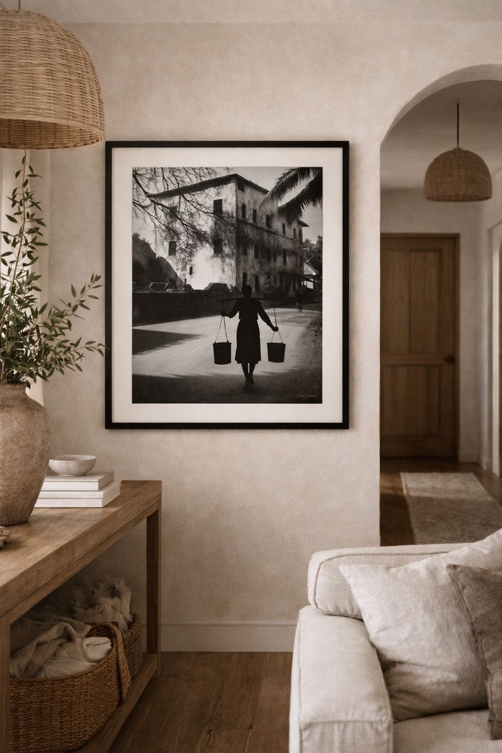 Black and white silhouette of a person carrying water buckets with strong shadow contrast in a cultural fine art style
