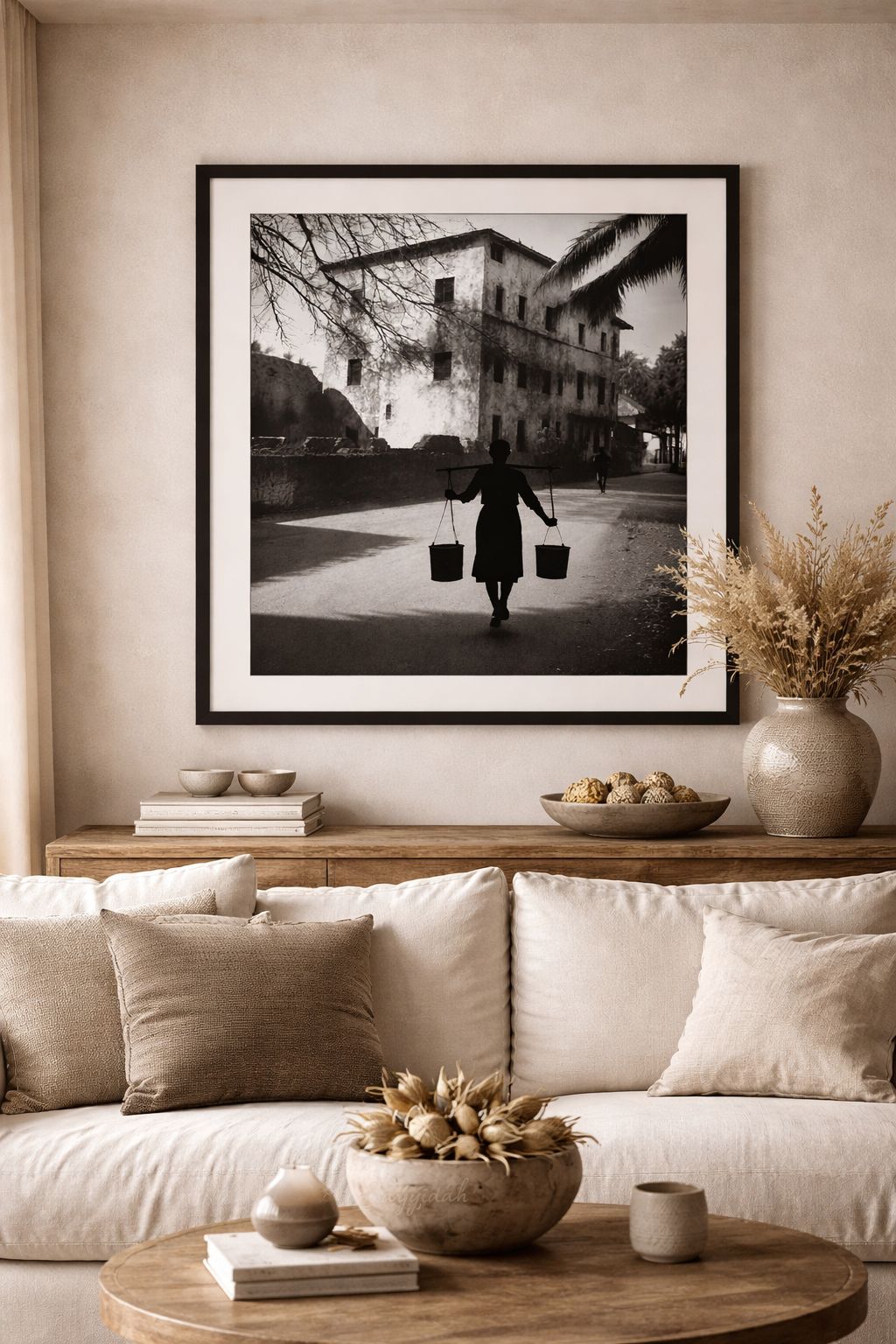 Black and white silhouette of a person carrying water buckets with strong shadow contrast in a cultural fine art style